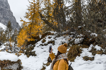 A female hiker wearing winter clothes, taking photos in a mountain in the Alps, Sloveniaの写真素材