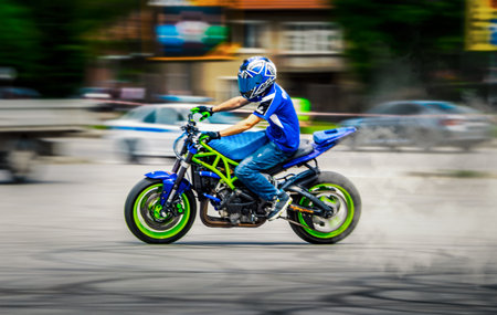 A scenic shot taken in motion of a blue and green motorcycle and a driver on itの写真素材