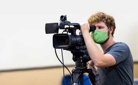 A young male Caucasian video operator with a green medical mask in the USAの写真素材