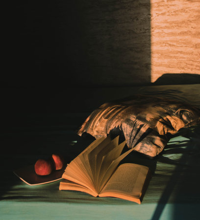 A closeup of an open book, peaches and a mesh bag on a tableの写真素材