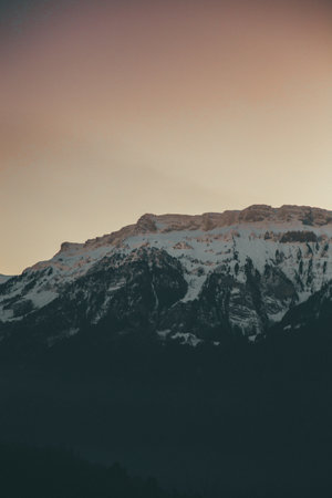 A vertical shot of snowy mountains at sunset in Switzerland