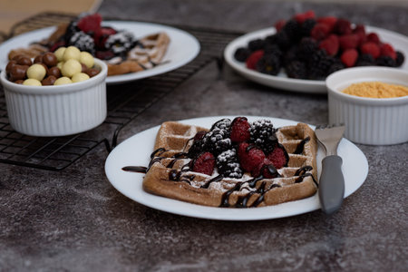 A photo of chocolate waffle with raspberries, a bowl of chocolate, and raspberries plateの写真素材