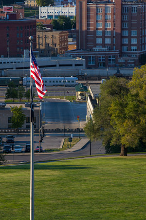 A vertical shot of an American flag in the park with a train in the background
