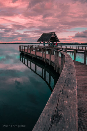 A wooden walkway over crystal clear waters at sunsetの写真素材