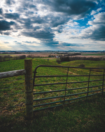 Dramatic sun rays shine through the clouds over a valley from the top of a hの写真素材
