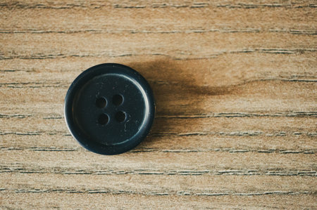 A closeup of a black button on a wooden surfaceの写真素材