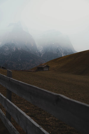 A vertical shot of an abandoned old wooden house in the mountains on a foggy dayの写真素材