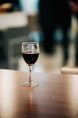 A vertical shot of a glass of white on a wooden table under the lightの写真素材