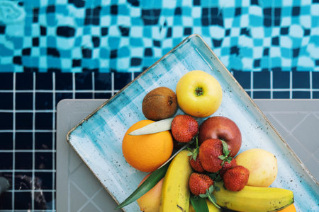 A plate of fruits on a background of tiles of a swimming poolの写真素材