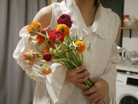 A woomen with a fashionable white drees holding colorful flowers
