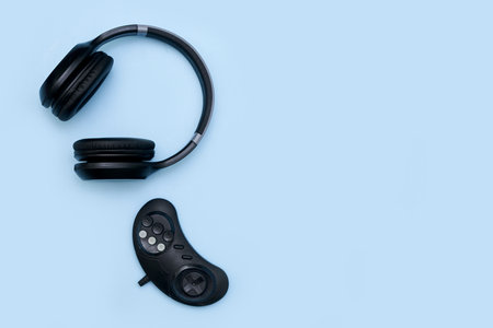 A top view shot of black headphones and a controller on a blue background