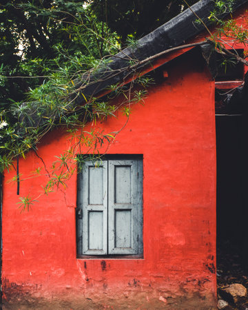 A closeup of a red old house with a white wooden windowの写真素材