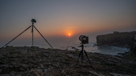 The cameras on tripods on the rocky coast set up for the sunrise photographing