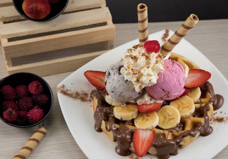 A top view of waffles served on a plate with strawberry, ice cream and bananasの写真素材