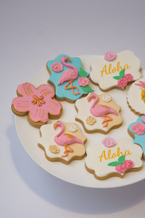A vertical photo of flamingo and flowers theme cookies on a white platterの写真素材