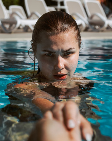 A beautiful Caucasian female enjoying time in a pool on a sunny dayの写真素材