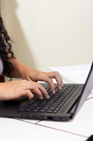 A vertical shot of a woman typing on her laptop on a desk