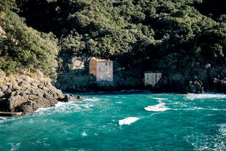 Two old houses in a small beautiful bay surrounded by rocks and greenery in San Fruttuoso, Italy