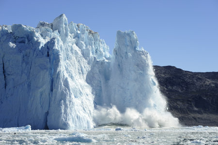 The melting glacier, iceberg falling into the sea. Northwestern Greenland.