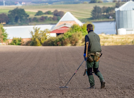 Metal detecting on newly sown field near a farmの写真素材