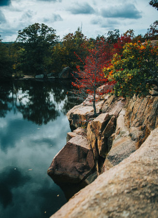 A vertical shot of a lake surrounded by elephant rocks and autumn trees in state park, Missouriの写真素材
