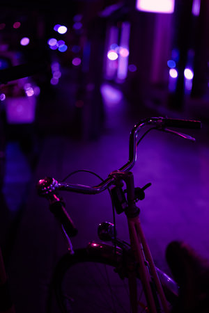 A vertical shot of a bicycle on the street with purple light during nighttime