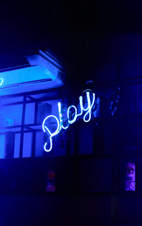 A vertical shot of a blue neon sign Playの写真素材