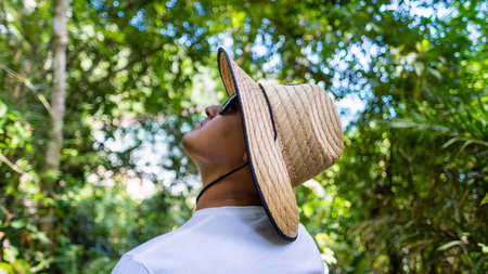 Young Latin man with typical Brazilian hat looking at the trees on vacationの写真素材