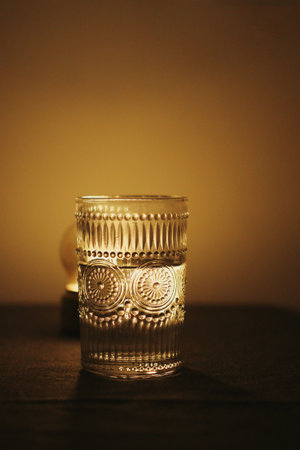 A vertical shot of a patterned glass next to a lamp, artsy aestheticの写真素材