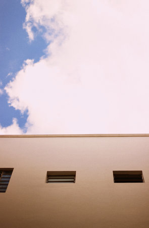 A vertical shot of a cloudy sky and a beige building
