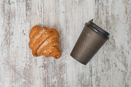 The fresh and appetizing croissant with a cup of tea on a wooden boardの写真素材