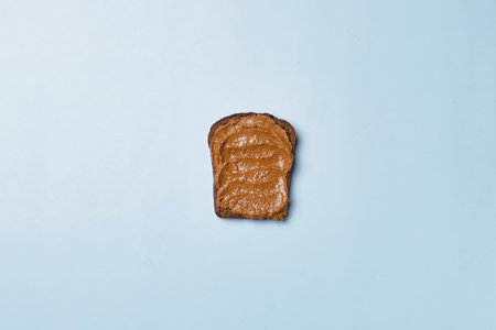 A top view of a slice of brown bread buttered with a tasty peanut butterの写真素材
