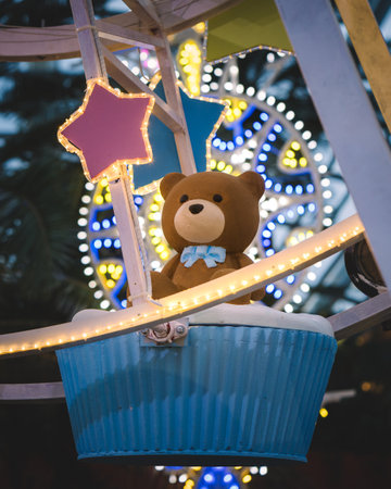 A closeup of A teddy bear sitting on a Ferris wheel with the shape of a cupcakeの写真素材