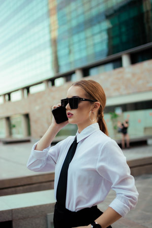 A blonde businesswoman with ponytail sunglasses and a classy outfit talking on the phoneの写真素材