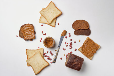 A closeup shot of peanut butter toasts and peanuts on a white background