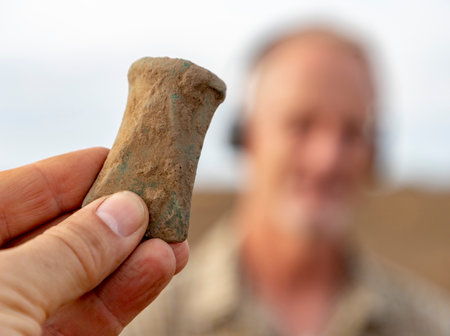 A bronze age axe found with metal detector, finder in the background