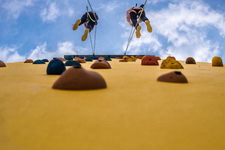 A  low-angle shot of a climbing exercise on a climbing wall hold with two hikers