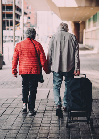 A vertical shot of an old couple holding hands while walkingの写真素材