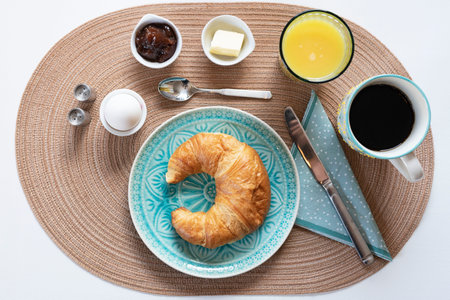 A top view of freshly-baked croissant on a porcelain plate with ingredients around itの写真素材