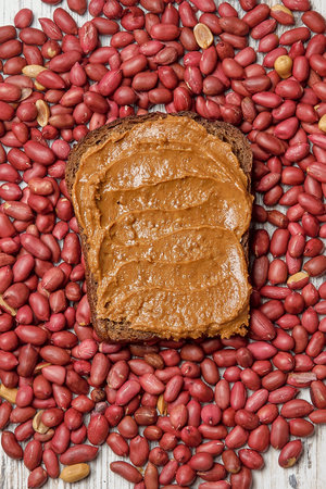 A closeup shot of peanut butter toast on the background of peanuts