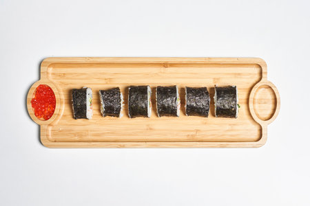 A top view of the fresh and appetizing maki sushi rolls served with red caviar on a wooden plateの写真素材