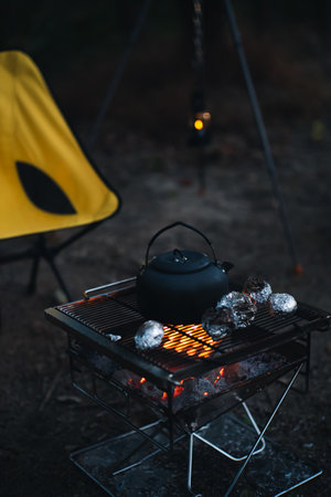 A vertical shot of a tea kettle boiling on grill gates on a blurred backgroundの写真素材