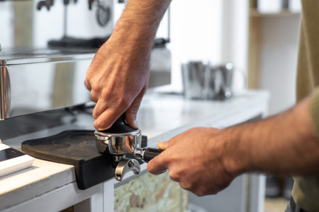 A closeup shot of a bartender holding a coffee tamper and compressing coffee groundsの写真素材