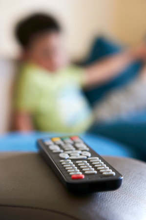 A vertical shot of a television remote control against a blurred person's background