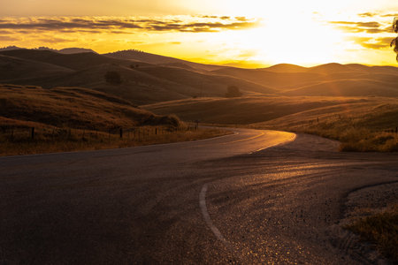 A scenic view of an asphalt road surrounded by small hills during sunset in Brazilの写真素材