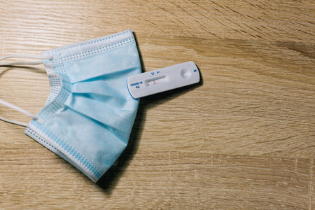 Surgical mask and negative coronavirus test on wooden background. Concept of safe vacation travel.の写真素材