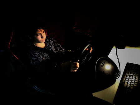 A Hispanic boy driving a video game car in a dark room in Spain