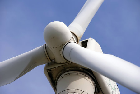 A closeup of the central part of a windmill against a blue sky