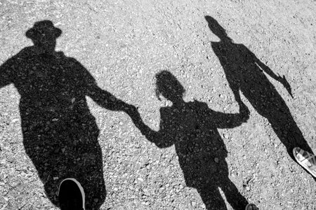 The family walking along the coast with their shadows visible on the pebble