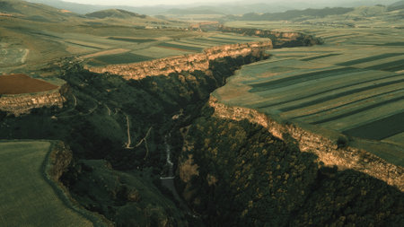 A natural landscape of the large green fields and a deep gorge with a river flowingの写真素材